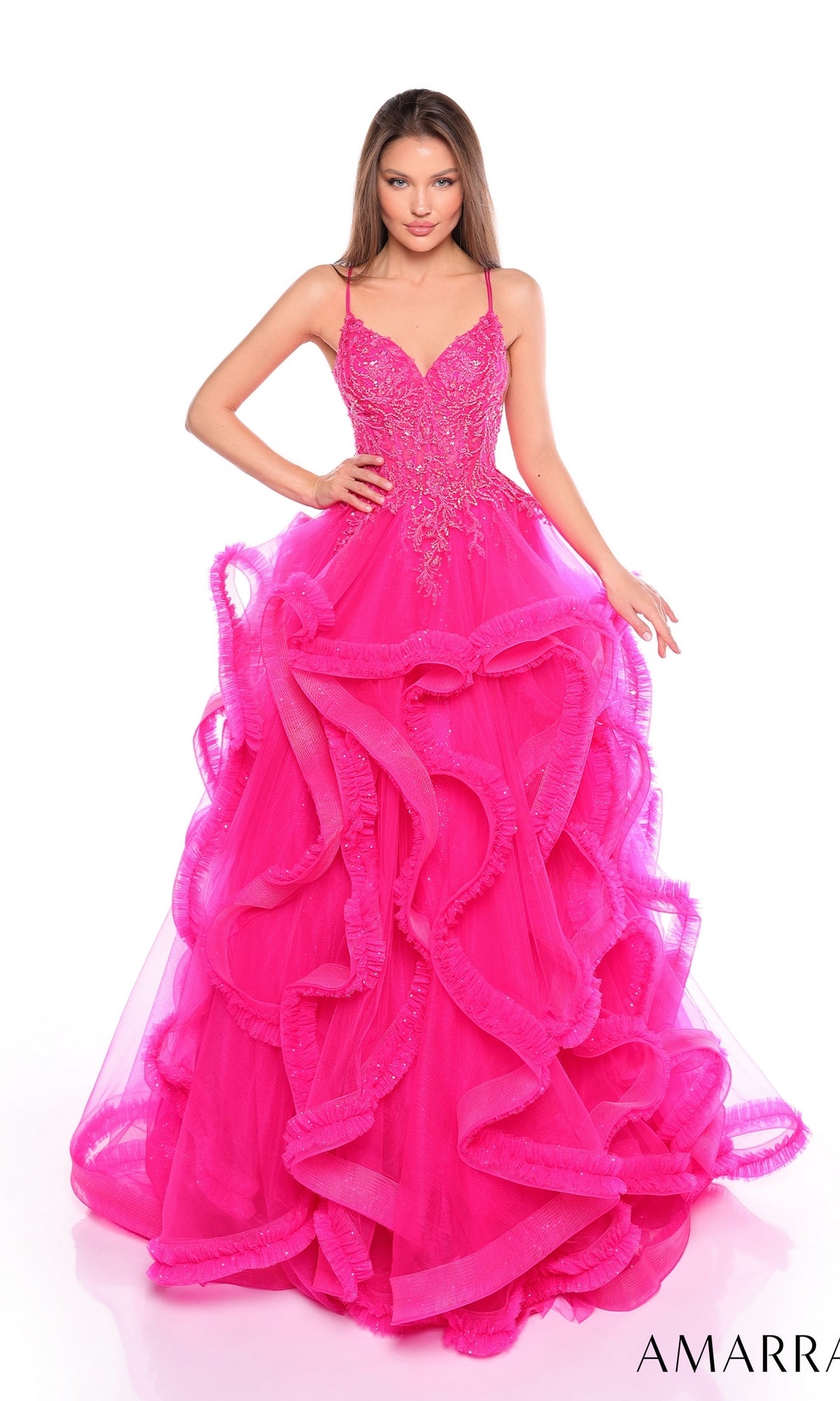 A woman wears the Amarra 88094 Ruffle Formal Ball Gown, featuring a bright pink color, fitted bodice with spaghetti straps, beaded embellishments, and a layered ruffled tulle skirt.